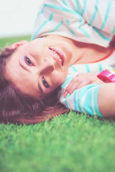 Mooie jonge vrouw liggend op het groene gras — Stockfoto