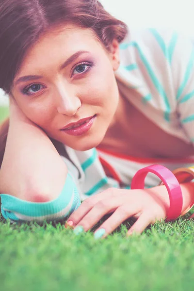 Mooie jonge vrouw liggend op het groene gras — Stockfoto