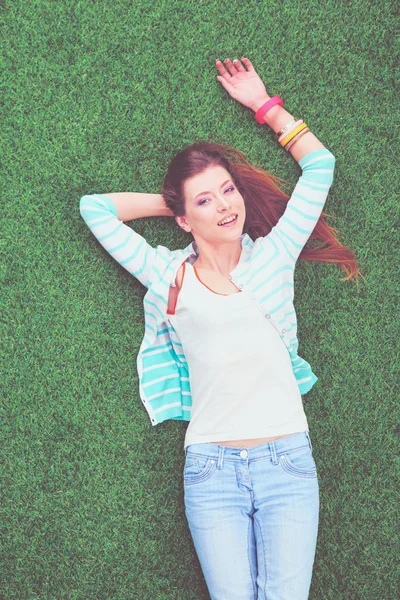 Mooie jonge vrouw liggend op het groene gras — Stockfoto