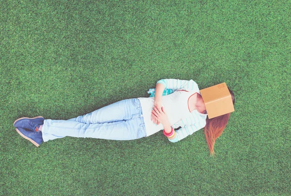 Mooie jonge vrouw liggend op het groene gras — Stockfoto
