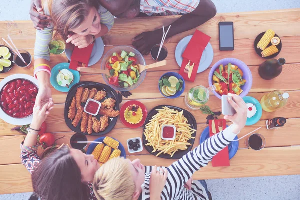 Top view of group of people having dinner together while sitting at wooden table. Food on the table. People eat fast food. — Stock Photo, Image