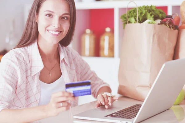 Mujer sonriente compras en línea utilizando tableta y tarjeta de crédito en la cocina. Mujer sonriente — Foto de Stock