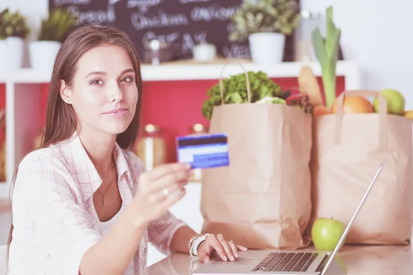 Mulher sorrindo compras on-line usando tablet e cartão de crédito na cozinha. Mulher sorridente — Fotografia de Stock