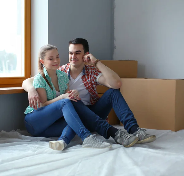 Couple moving in house sitting on the floor. Couple