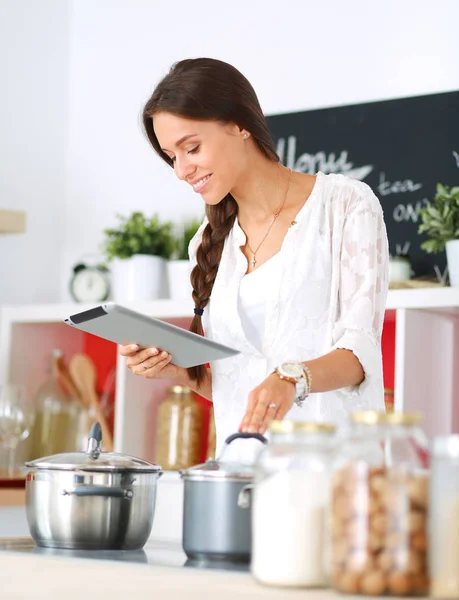 Mujer joven usando una tableta para cocinar en su cocina —  Fotos de Stock