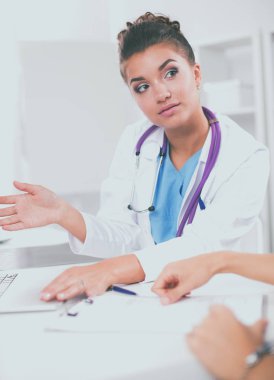 Doktor ve hasta ofiste masada oturuyorlar.