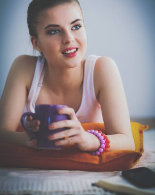 yastık ile beyaz bir yerde yatarken gülümseyen genç kadın