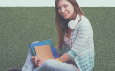 Yeşil çimenlerin üzerinde oturan güzel genç kadın