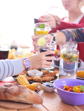 Ahşap masada otururken birlikte yemek yiyen bir grup insanın üst düzey görüntüsü. Masada yemek var. İnsanlar fast food yiyor..