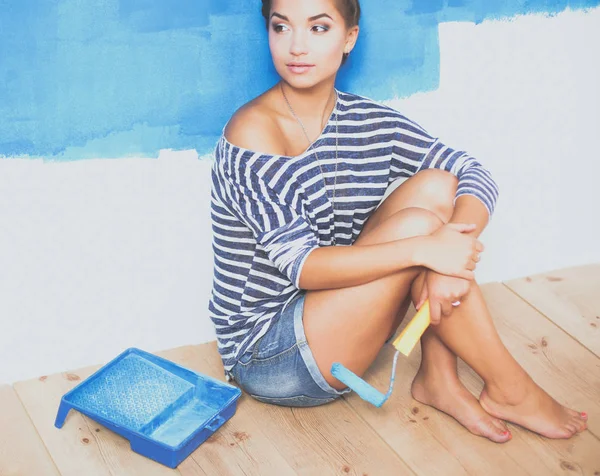 Portret malarza kobieta siedzi na podłodze w pobliżu ściany po malowaniu — Zdjęcie stockowe