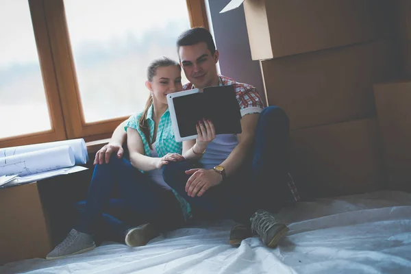 Par som flyttar i huset sitter på golvet med ipad. Par — Stockfoto