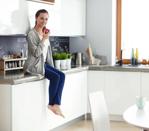 Kvinna med mobiltelefon sitter i moderna kök. — Stockfoto