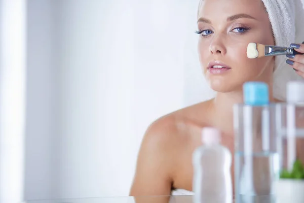 浴室に顔の粉を塗る若い女性の写真 — ストック写真