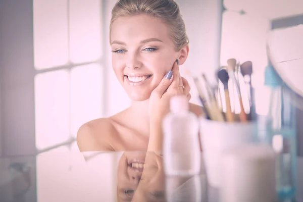 Giovane donna in accappatoio guardando nello specchio del bagno — Foto Stock