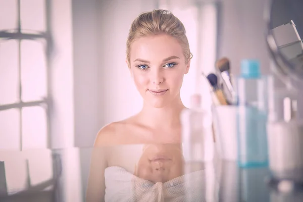 Giovane donna in accappatoio guardando nello specchio del bagno — Foto Stock