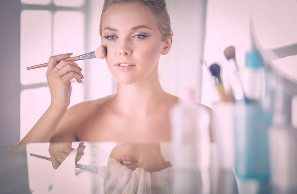 Una foto di una giovane donna che applica polvere per il viso in bagno — Foto Stock