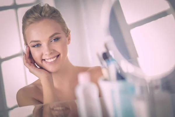 Jonge vrouw in badjas op zoek in badkamer spiegel — Stockfoto