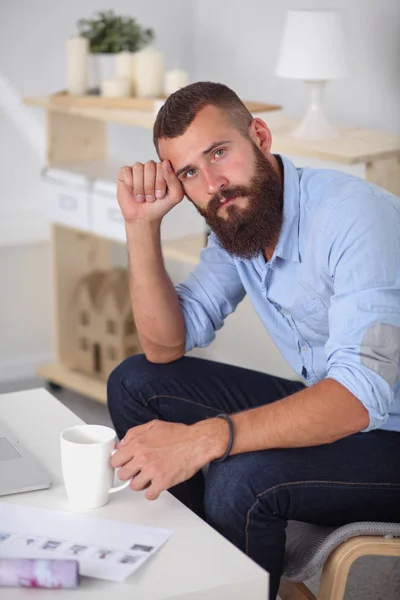 Молодой бизнесмен сидит на стуле в офисе — стоковое фото
