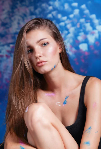 Young beautiful woman sitting near painting wall — Stock Photo, Image