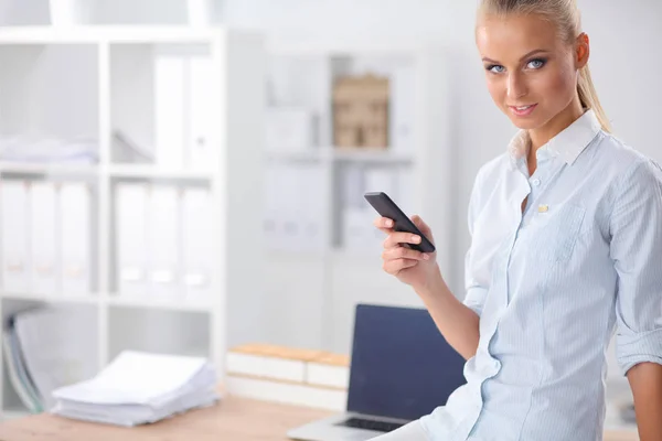 Zakenvrouw stuurt bericht met smartphone op kantoor — Stockfoto