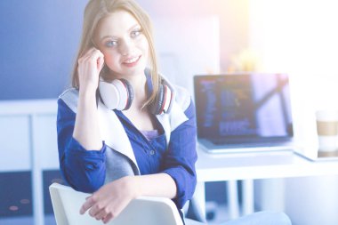 Ofis masasında çalışan ve dizüstü bilgisayarla yazan kendine güvenen genç bir iş kadını.