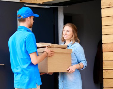 Mavi üniformalı gülümseyen kurye servis konseptine paket kutusu teslim eden teslimatçı. Mavi üniformalı gülümseyen teslimatçı.