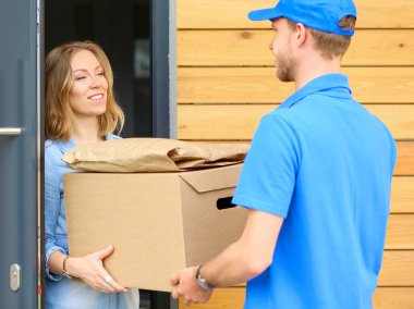 Mavi üniformalı gülümseyen kurye servis konseptine paket kutusu teslim eden teslimatçı. Mavi üniformalı gülümseyen teslimatçı.