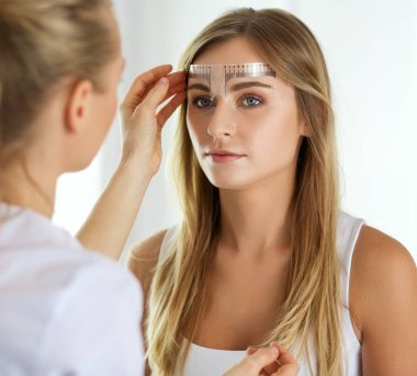 Kaşlar için kalıcı makyaj. Güzellik salonunda kalın kaşlı güzel bir kadın..