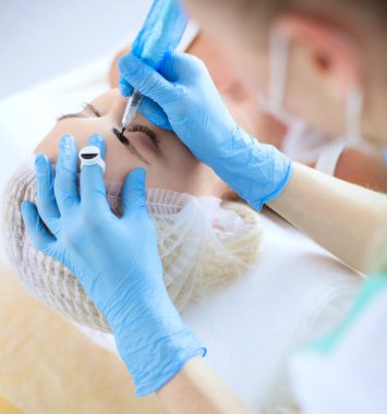 Kaşlar için kalıcı makyaj. Güzellik salonunda kalın kaşlı güzel bir kadın..