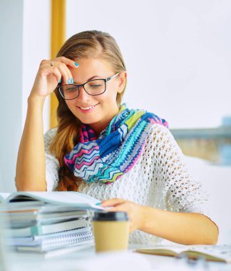 Kitapların arasında masa başında oturan genç bir kadın.