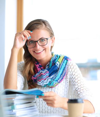 Kitapların arasında masa başında oturan genç bir kadın.