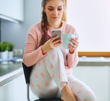 modern mutfakta otururken cep telefonu kullanan kadın