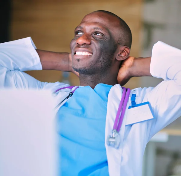 Jeune médecin africain travaillant sur ordinateur portable au bureau — Photo