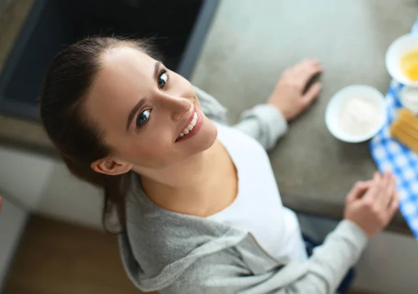 Hermosa mujer cocinando pastel en la cocina de pie cerca del escritorio — Foto de Stock