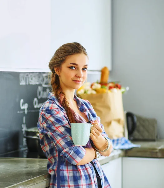 Szczęśliwa kobieta picia herbaty w kuchni w domu — Zdjęcie stockowe
