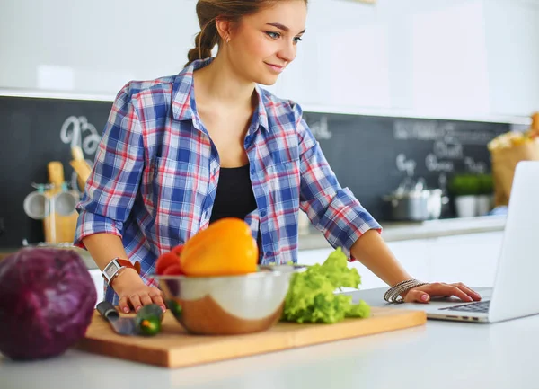 Молодая женщина режет овощи на кухне возле стола — стоковое фото