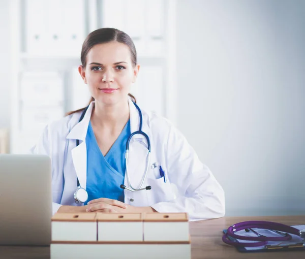 Όμορφη νεαρός χαμογελαστό γυναίκα γιατρό κάθεται στο γραφείο και το γράψιμο. γυναίκα γιατρό — Φωτογραφία Αρχείου