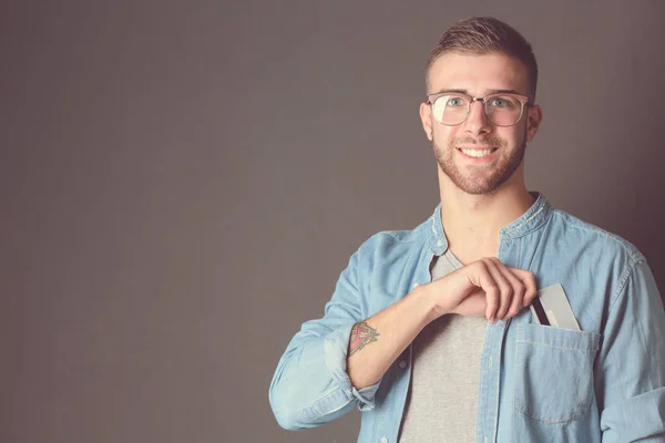 Young man holding a credit card standing on gray background. Young entrepreneur. — Stock Photo, Image