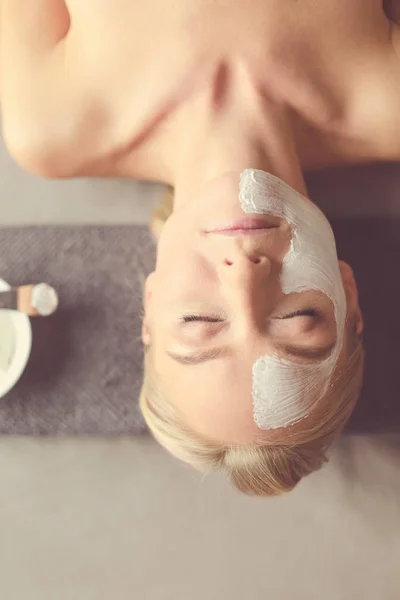 Gezichtsmasker. Mooi jong meisje in spa, schoonheidsspecialist vrouw gezicht masker toe te passen. — Stockfoto