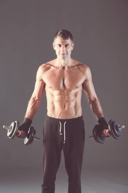 Yakışıklı kaslı adam dumbell ile çalışma dışarı. Kişisel fitness eğitmeni. Kişisel eğitim.