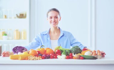 Ahşap iç kısımda meyve ve sebze dolu masada oturan genç ve tatlı bir kadın..