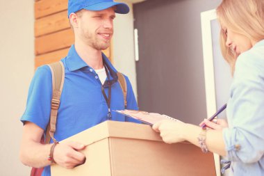 Mavi üniformalı gülümseyen kurye servis konseptine paket kutusu teslim eden teslimatçı. Mavi üniformalı gülümseyen teslimatçı.