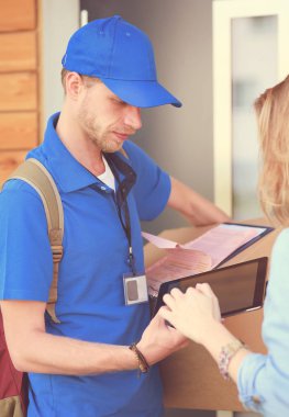 Mavi üniformalı gülümseyen kurye servis konseptine paket kutusu teslim eden teslimatçı. Mavi üniformalı gülümseyen teslimatçı.