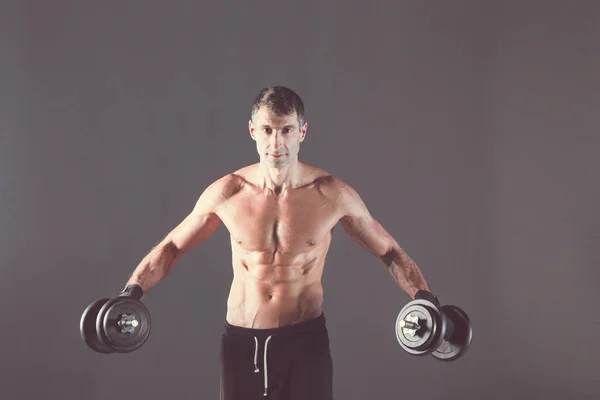 Красивый мускулистый мужчина, тренирующийся с гантелями. Персональный тренер по фитнесу. Личное обучение . — стоковое фото