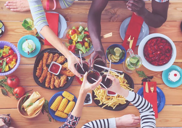 Top view of group of people having dinner together while sitting at wooden table. Food on the table. People eat fast food. — Stock Photo, Image