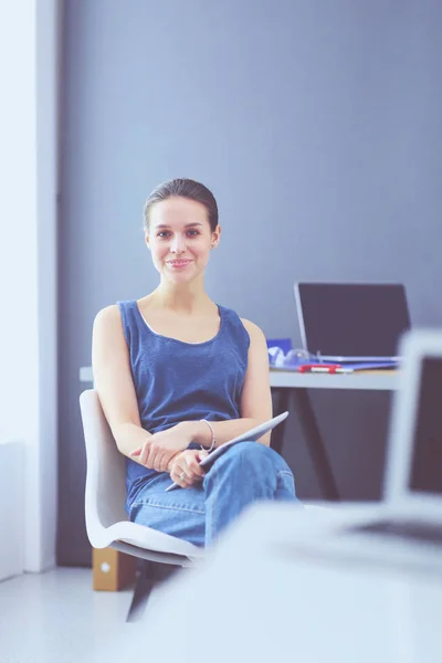 Jonge vrouw zit aan het bureau met instrumenten, plan en laptop. — Stockfoto