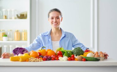 Ahşap iç kısımda meyve ve sebze dolu masada oturan genç ve tatlı bir kadın..