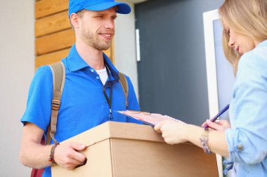 Mavi üniformalı gülümseyen kurye servis konseptine paket kutusu teslim eden teslimatçı. Mavi üniformalı gülümseyen teslimatçı.