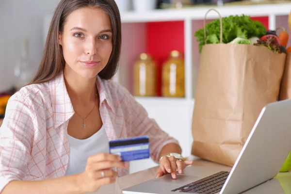 Улыбающаяся женщина онлайн покупки с помощью планшета и кредитной карты на кухне. Улыбающаяся женщина — стоковое фото