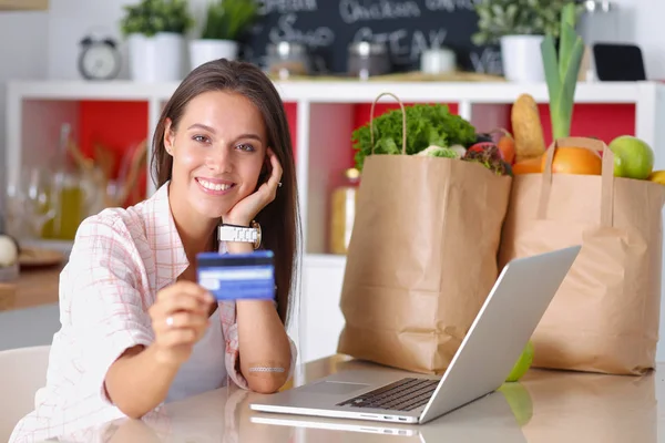 Mulher sorrindo compras on-line usando tablet e cartão de crédito na cozinha. Mulher sorridente — Fotografia de Stock